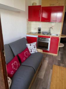 萨莫安斯Samoëns 1600 les cimes的一个带红色橱柜的小厨房内的沙发