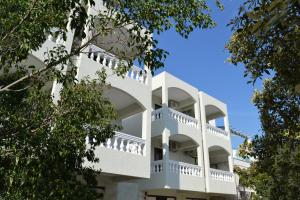 波罗斯To Spiti Tis Eirinis的公寓大楼设有白色阳台和树木