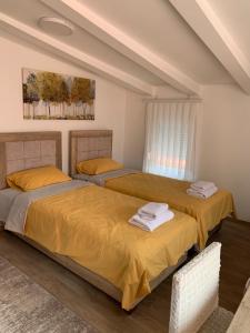 新帕扎尔Centar Bruno的卧室内的两张床,配有黄色床单