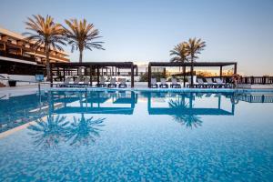 雷塔马尔巴塞罗加塔角酒店的一个带椅子和棕榈树的大型游泳池