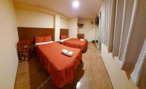 瓦努科Lembranças Hotel的酒店客房设有两张床、一张书桌和窗户。