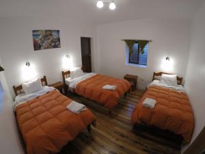 库斯科Tucan Hostel的带3张床和橙色床单的客房