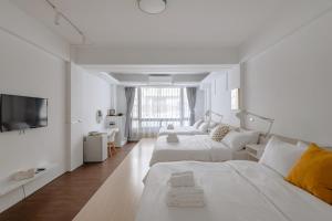 花莲市藍色知更鳥旅宿的白色的客厅配有两张床和电视