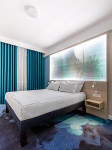 加拉茨ibis Styles Dunarea Galati的一间卧室配有一张带蓝色窗帘的大床