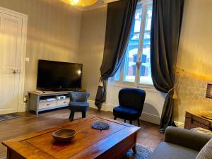罗莫朗坦la Porte aux Dames的客厅配有电视和桌椅