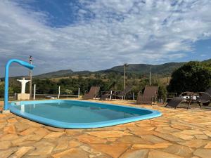 卡皮托利乌Pousada Império de Minas的一座位于庭院内的游泳池,庭院内以群山为背景