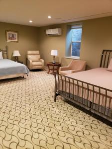 WinamacMill Creek Gardens的一间卧室设有两张床、一把椅子和一个窗户。