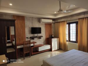 古鲁瓦尤尔Hotel Sree Gokulam Apartments的一间卧室配有一张床、一张书桌和一台电视