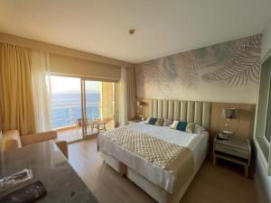 库萨达斯魅力豪华酒店的一间卧室设有一张大床和一个大窗户