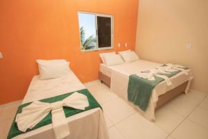 雅帕拉廷加Flat Bela Vista的橙色墙壁的客房内的两张床