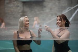 坦普尔帕特里克The Rabbit Hotel & Retreat的两个女人在游泳池里拿着酒杯