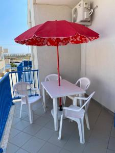 维拉诺瓦casa patrizia的阳台配有带红伞的桌椅