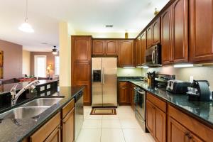 奥兰多4Br 2Bath Condo Balcony 5min Conv Center 2020ft的厨房配有木制橱柜和不锈钢冰箱。