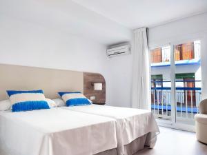 贝尼多姆Hotel Flats Friends Mar Blau的白色卧室配有一张带蓝色枕头的大床