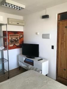 科洛尼亚-德尔萨克拉门托Suite Artigas的一间白色橱柜内配有电视的卧室