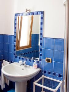 圣玛丽亚巴格诺B&B La Spiaggetta的蓝色瓷砖浴室设有水槽和镜子