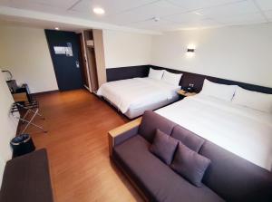 台东富裕商旅 RICH-hotel的酒店客房,设有两张床和一张沙发