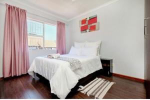 米德兰The Resting Nest的一间卧室配有床和一个带粉红色窗帘的窗户。