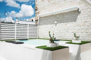 普蒂尼亚诺Ulivi Bianchi Luxury Home in Puglia的一个带两个仙人掌和砖墙的游泳池