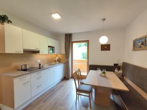圣洛伦佐-迪塞巴托Pramstaller Apartments的厨房配有白色橱柜和桌椅