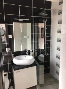栋博堡Cuki Apartmanok的一间带水槽和玻璃淋浴的浴室