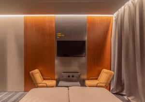 基辅Дизайн-готель ROAD的一间卧室配有一张床、两把椅子和一台电视