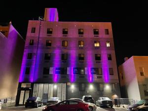 布鲁克林King Hotel Brooklyn Sunset Park的建筑的侧面有紫色的灯