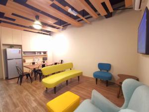 新山Maco Inn Austin Heights @Johor Bahru的客厅配有黄色和蓝色的椅子和桌子