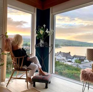 拉恩Ballygally Seaview Cottage的坐在椅子上看着窗外的女人
