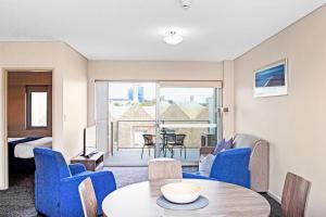阿德莱德胡美服务式公寓的一间配备有蓝色椅子和一张桌子的客厅,享有美景。