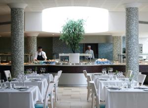 利马索尔Atlantica Oasis Hotel的一间配备有白色桌椅的用餐室和一间厨房