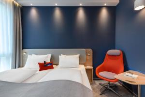 雷根斯堡Holiday Inn Express - Regensburg, an IHG Hotel的酒店客房,配有一张床和一张红色椅子