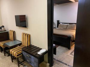 木尔坦City Centre Suites的一间卧室配有一张床、镜子和椅子