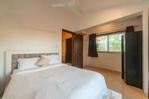 安君纳Goa Junction by Daystar Ventures的卧室设有一张白色大床和一扇窗户。