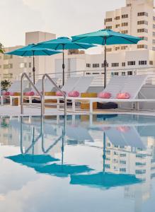 迈阿密海滩Hotel Greystone - Adults Only的大楼内带桌子和遮阳伞的游泳池