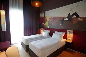 泰尔托Grimm´s Berlin Potsdam的酒店客房设有两张床,墙上挂有绘画作品