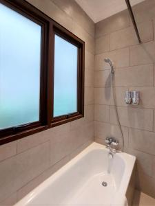 雅加达Via Renata Prapanca的带2扇窗户的浴室内的白色浴缸