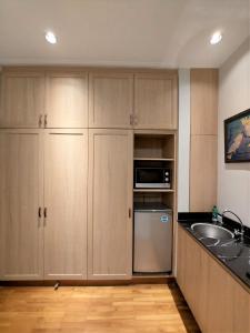 雅加达Via Renata Prapanca的厨房配有木制橱柜、水槽和微波炉