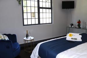 圣约翰港Uzuri Lifestyle的一间卧室配有一张床、一把蓝椅和一个窗户。