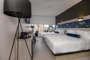 瓜亚基尔River Garden Hotel + Suites的酒店客房,设有两张床和一盏灯