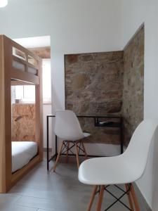 塞尔唐Hostel Sertã的卧室配有2把白色椅子和1张双层床。