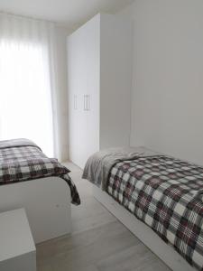 利多迪耶索罗Jesolo Appartamenti F2 - Light Blue的一间白色卧室,配有一张床和一张铺着地毯的毯子