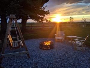 博兹曼Gallatin Gateway Getaway的火坑,带椅子和桌子,享有日落美景