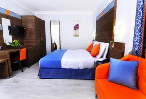 科托努Benin Royal Hotel的一间卧室配有一张床和两张橙色椅子