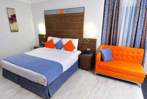 科托努Benin Royal Hotel的一间卧室配有一张床和一张橙色椅子