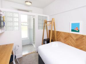 法尔茅斯The Broadmead的一间卧室配有一张床、一张书桌和一个窗户。