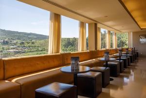 吉马良斯帆迪朵酒店的餐厅的一排桌子和凳子,设有大窗户