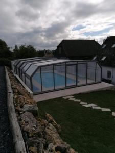 BucillyGîte La feuille d'Acanthe的一座玻璃房子,在院子里设有游泳池