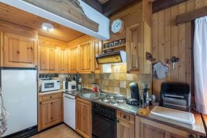 莫尔金斯Chalet ChouChou的厨房配有木制橱柜和白色冰箱。