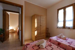 佩斯科勒海滨Tenuta Li Fani Residence Hotel的一间卧室设有两张床、一个橱柜和窗户。
